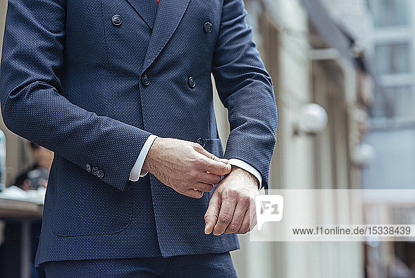 Man wearing double-breasted suit adjusting his cuff