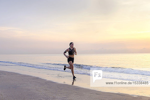 Woman jogging on beach at sunset