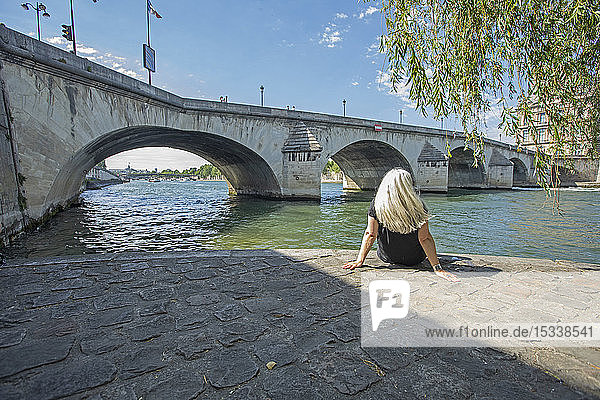 Frau sitzt an einer Brücke über die Seine in Paris  Frankreich
