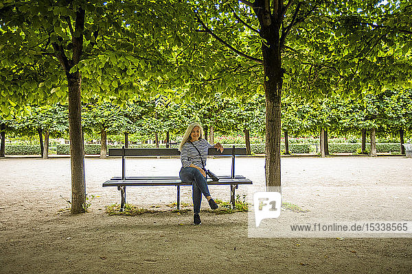 Frau auf Parkbank unter Bäumen in den Palais-Royal-Gärten in Paris  Frankreich