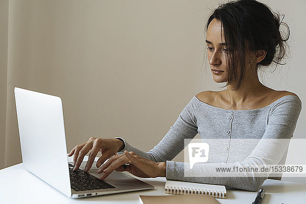 Woman using laptop with note pads