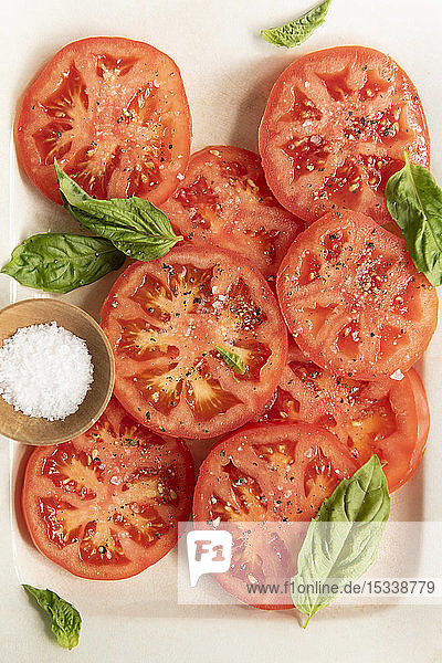 In Scheiben geschnittene Tomaten mit Basilikum und Salz
