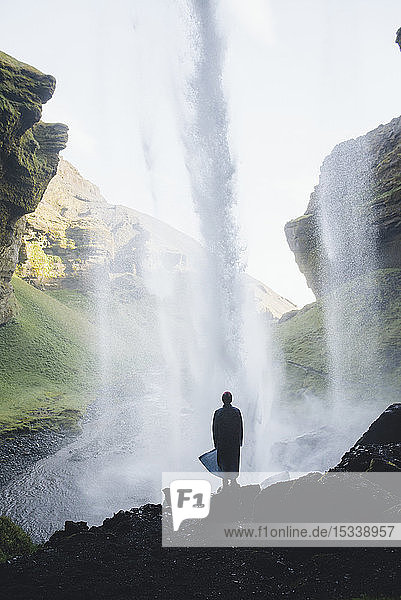 Silhouette eines Mannes hinter dem Kvernufoss-Wasserfall in Island