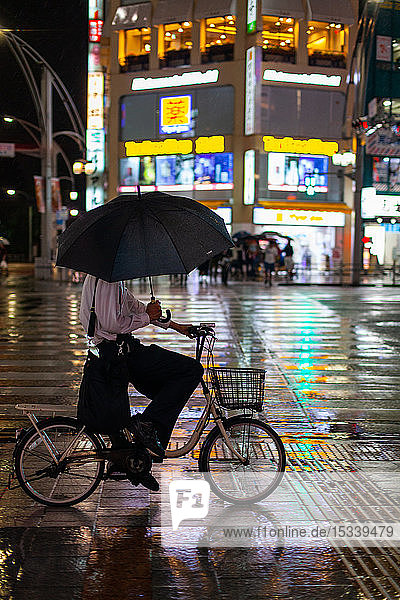 Mann fährt in einer regnerischen Nacht Fahrrad