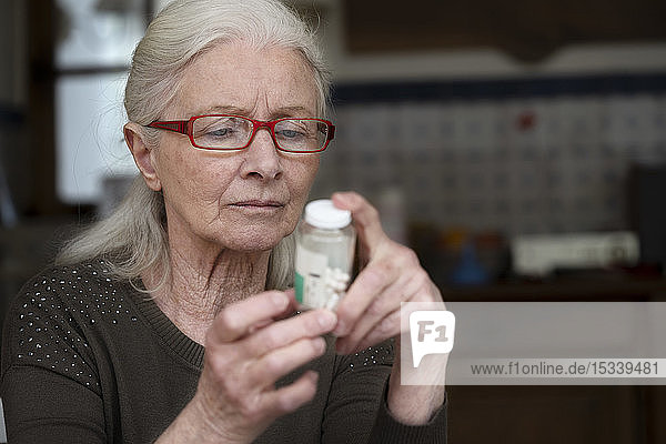Frau liest Etikett einer Pillenflasche