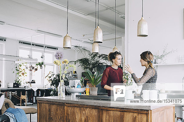 Creative businesswomen discussing at kitchen island in office