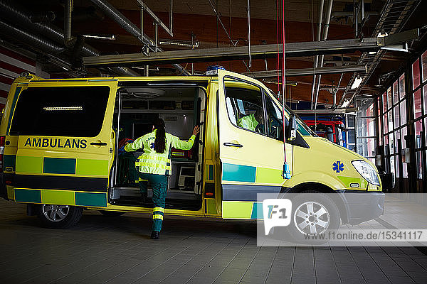 Weibliche Rettungssanitäterin steigt am Parkplatz in einen Krankenwagen