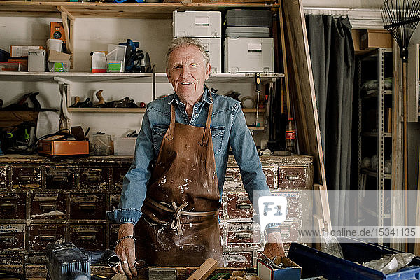 Porträt eines selbstbewusst lächelnden älteren männlichen Eigentümers beim Workshop stehend