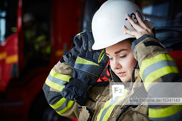Female firefighter wearing helmet while looking down at fire station