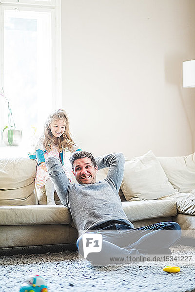 Fröhlicher Vater und Tochter spielen zu Hause im Wohnzimmer