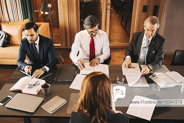 Hoher Blickwinkel auf weiblichen Finanzberater bei der Planung mit männlichen Anwälten bei einem Treffen im Sitzungssaal