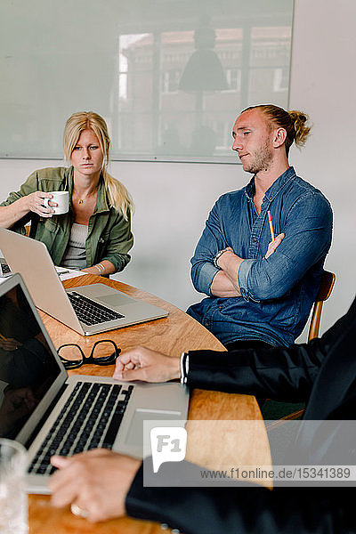 Männliche und weibliche Mitarbeiter schauen während des Brainstormings im Büro auf den Laptop
