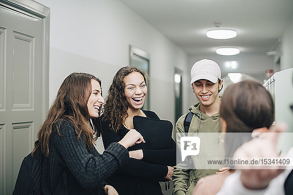 Fröhliche jugendliche Studenten stehen im Korridor