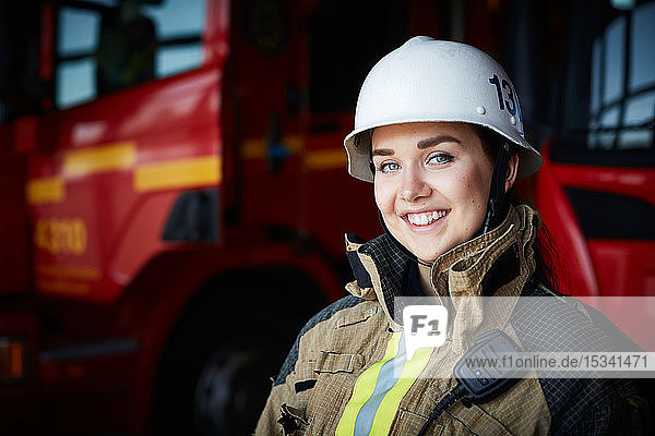 Porträt einer lächelnden Feuerwehrfrau mit Helm in der Feuerwache