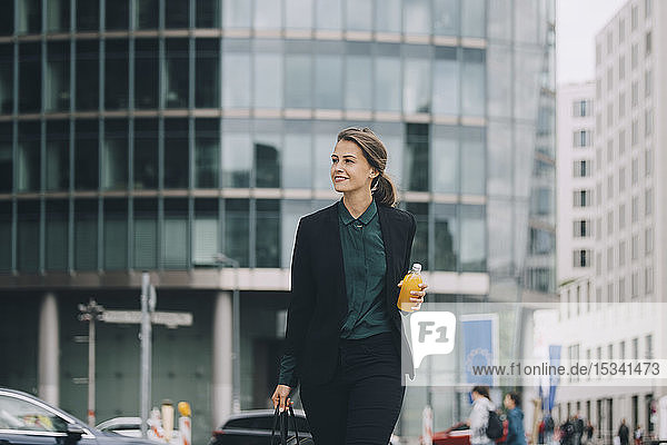 Confident businesswoman looking away while walking in city