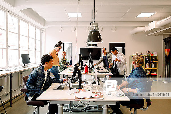 Kreative männliche und weibliche Geschäftskollegen  die im Großraumbüro arbeiten