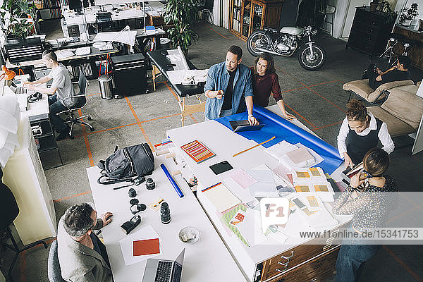 Blick aus der Vogelperspektive auf kreative Geschäftsleute und Geschäftsfrauen  die am Tisch im Büro arbeiten