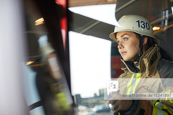 Zuversichtliche Feuerwehrfrau im Feuerwehrauto sitzend