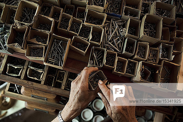 Direkt über der Ansicht einer älteren Verkäuferin  die Nägel aus einem Karton im Baumarkt entfernt