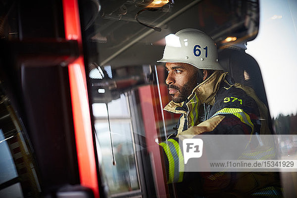 Confident firefighter looking away while sitting in fire engine