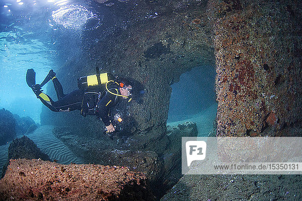 Scuba diver swimming through submerged ancient Roman ruins Dragonara caves Miseno Campi Flegrei (Phlegraean Fields) Campania Italy Europe