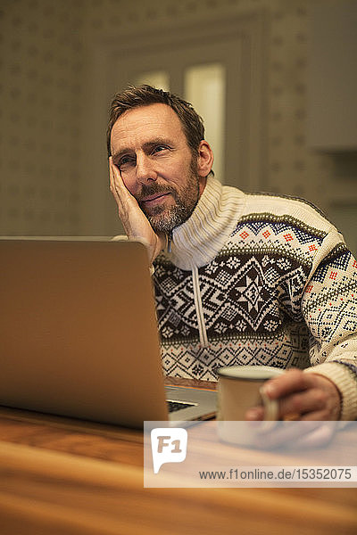 Casual businessman using laptop on table at home