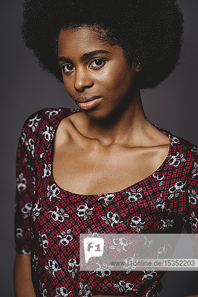 Junge Frau mit afrofarbenen Haaren vor grauem Hintergrund
