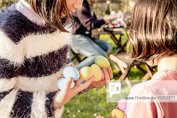 Zwei Mädchen mit einer Handvoll gefärbter Ostereier bei Tisch  beschnitten