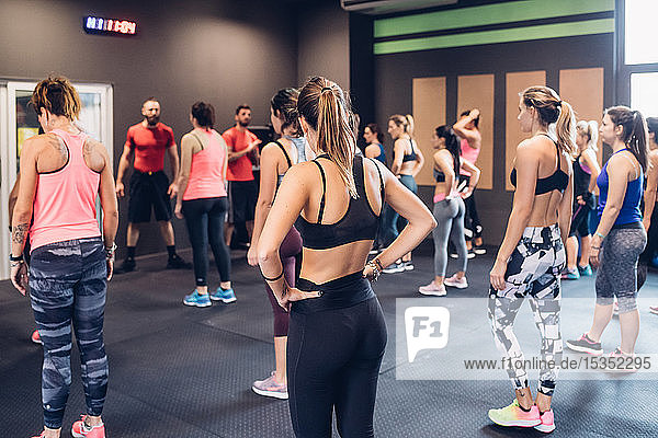 Gruppe von Frauen  die im Fitnessstudio mit männlichen Trainern trainieren
