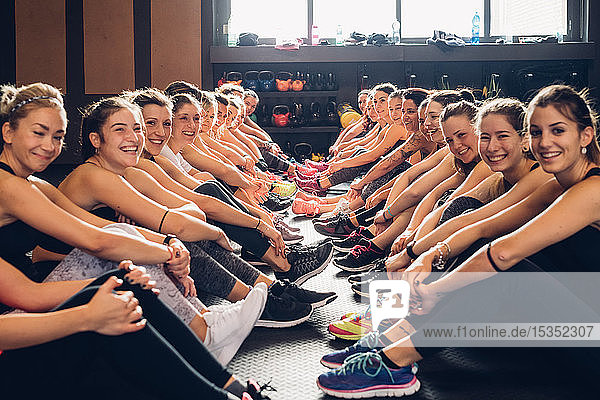 Große Gruppe von Frauen trainiert in Turnhalle  auf dem Boden sitzend  Porträt