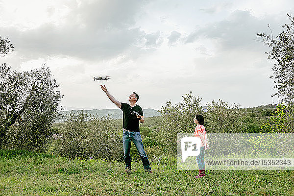 Mädchen beobachtet Vater fliegende Drohne in malerischer Feldlandschaft  Citta della Pieve  Umbrien  Italien