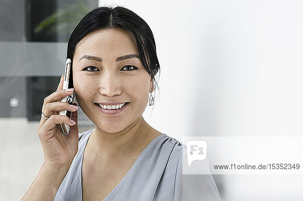 Geschäftsfrau mit Smartphone vor weißer Wand im Büro