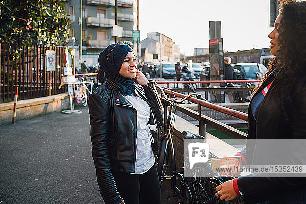 Junge Frau im Hidschab im Gespräch mit Freundin in der Stadt