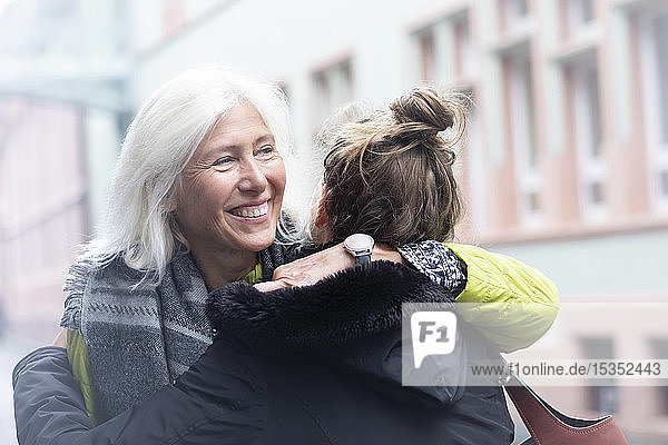Reife Frau und Tochter umarmen sich auf der Straße in der Stadt