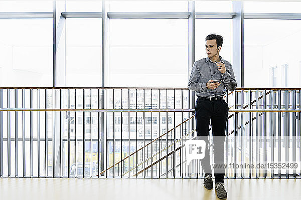 Businessman using smartphone in office corridor