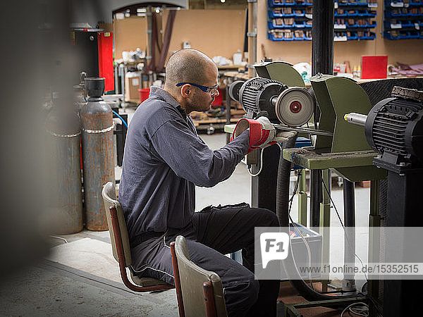 Knife factory worker using angle grinder in workshop