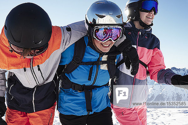 Skiers  mother with teenage son and daughter with arms around each other on snow covered mountain top  Alpe-d'Huez  Rhone-Alpes  France
