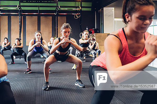 Group of women training in gym  squatting