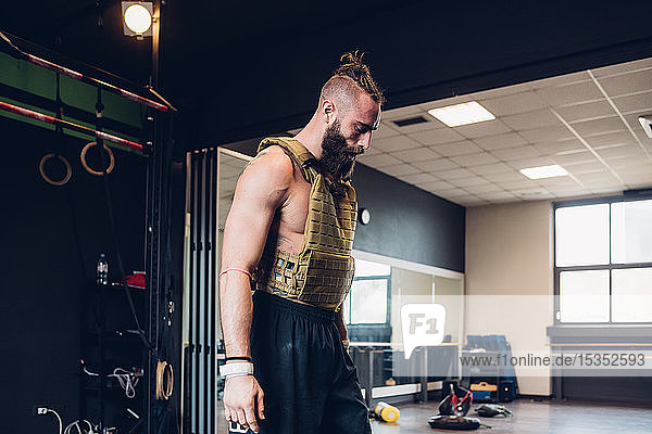 Young man training in gym  wearing weight vest