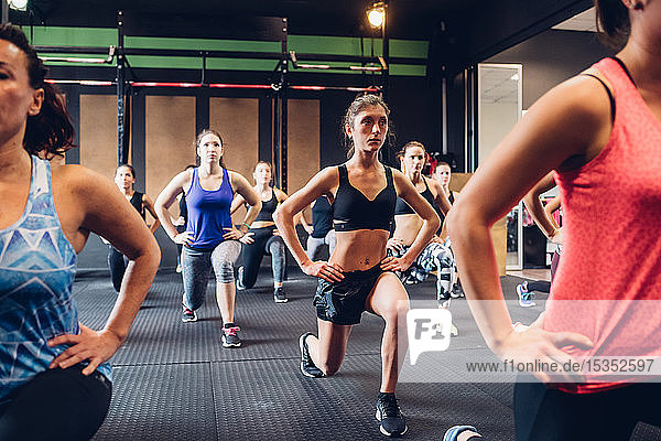 Gruppe von Frauen  die im Fitnessstudio trainieren  mit ausgestreckten Händen auf Hüften und Beinen  Vorderansicht