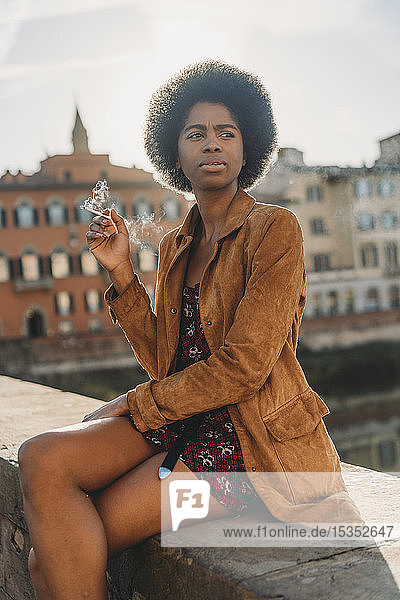 Young woman with afro hair smoking on bridge  Florence  Toscana  Italy