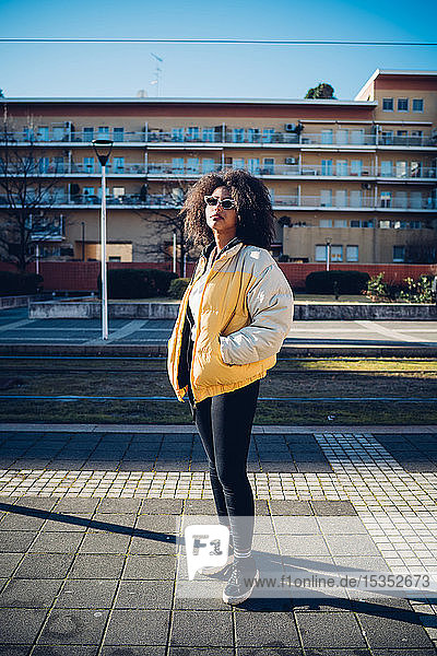 Coole junge Frau mit Sonnenbrille auf städtischem Bürgersteig stehend  Porträt