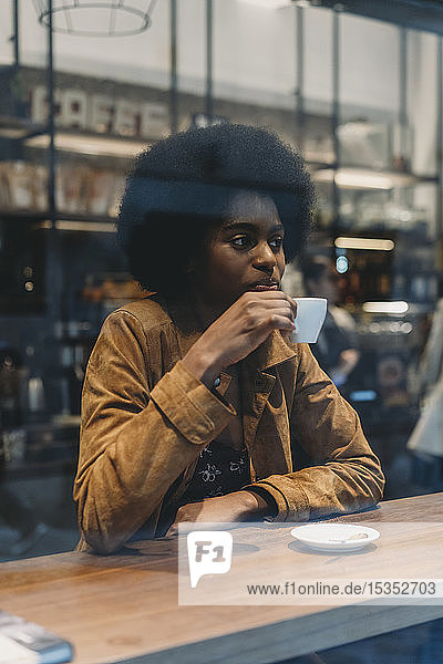 Young woman with afro hair having coffee in cafe