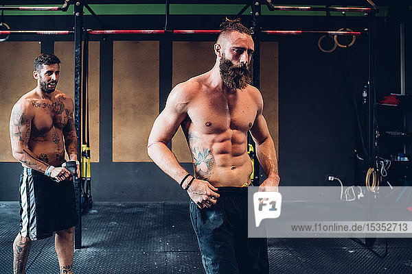 Young tattooed men training in gym taking a break
