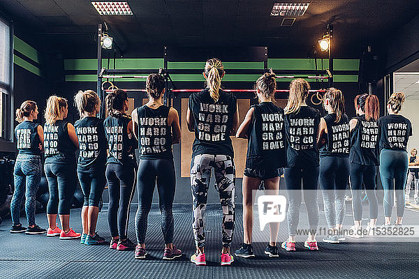 Group of women training in gym  wearing slogan t-shirts  rear view