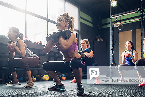 Women training in gym  squatting with kettle bells