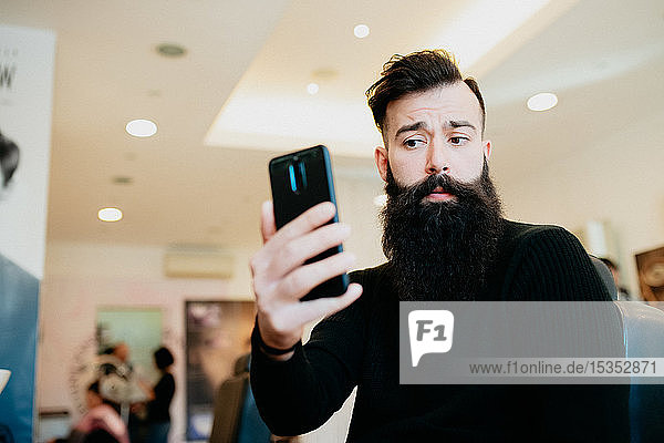 Bearded man taking selfie in barber shop