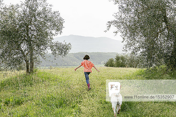 Mädchen rennt mit Labradorhund in malerischer Feldlandschaft  Rückansicht  Citta della Pieve  Umbrien  Italien