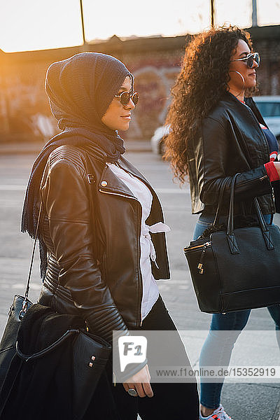 Young woman in hijab and best friend strolling in city