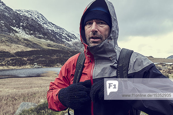 Male hiker with hood up in snow capped mountain landscape  portrait  Llanberis  Gwynedd  Wales